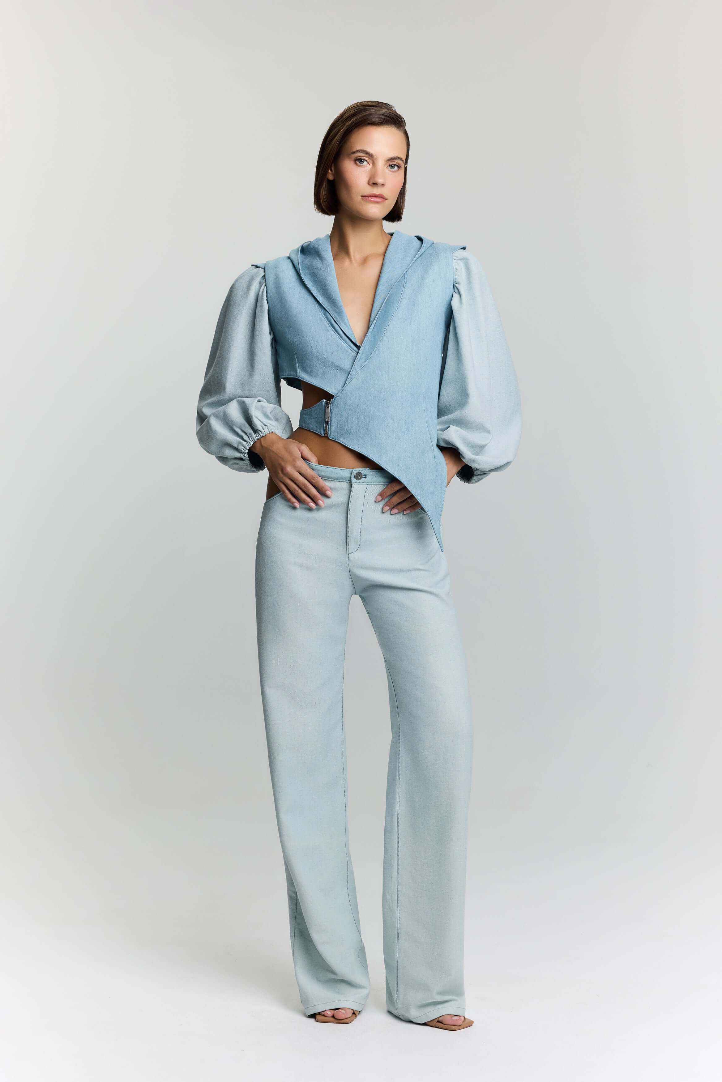 JENDUE Modern light blue denim vest jacket with an edgy asymmetrical design and contrasting fabric sleeves.