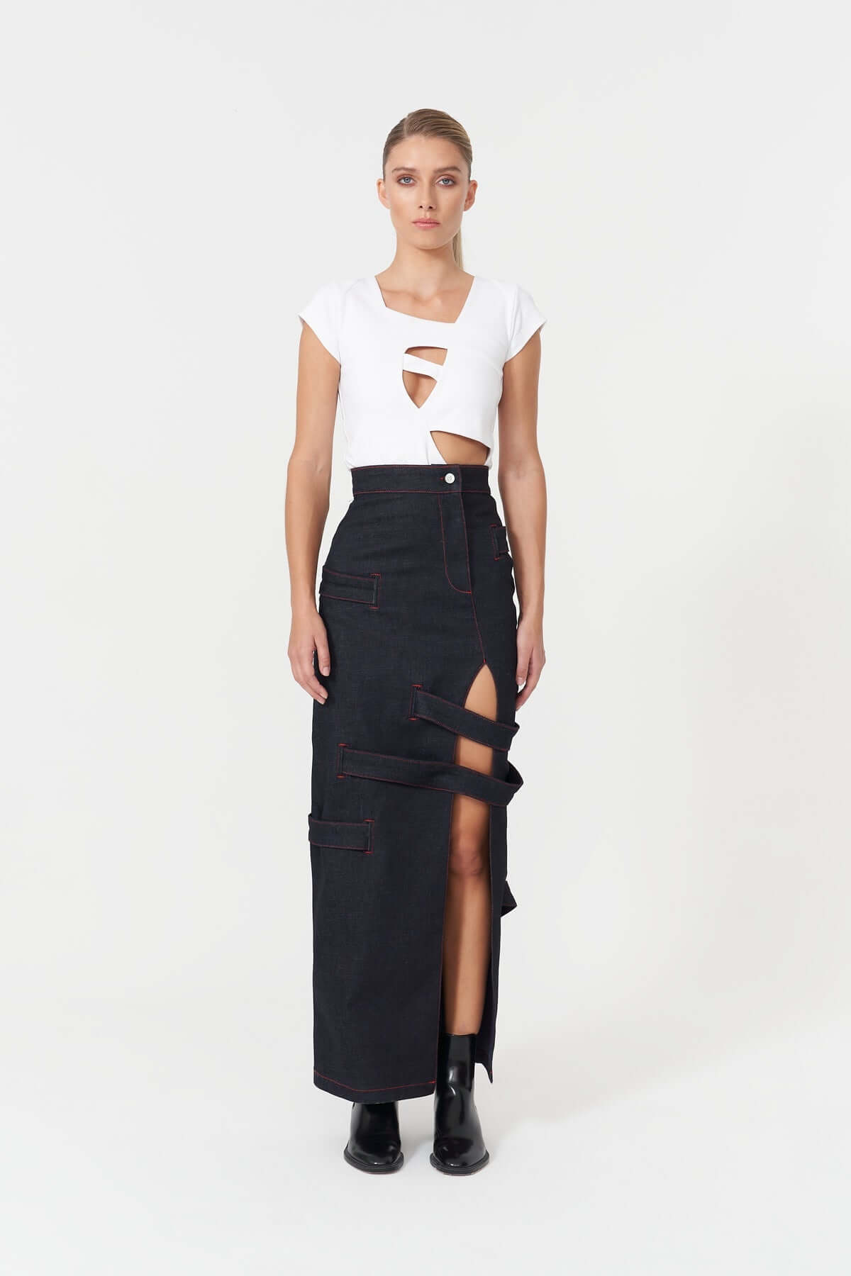 JENDUE Stylish dark blue denim long skirt featuring a front slit and unique strap details.