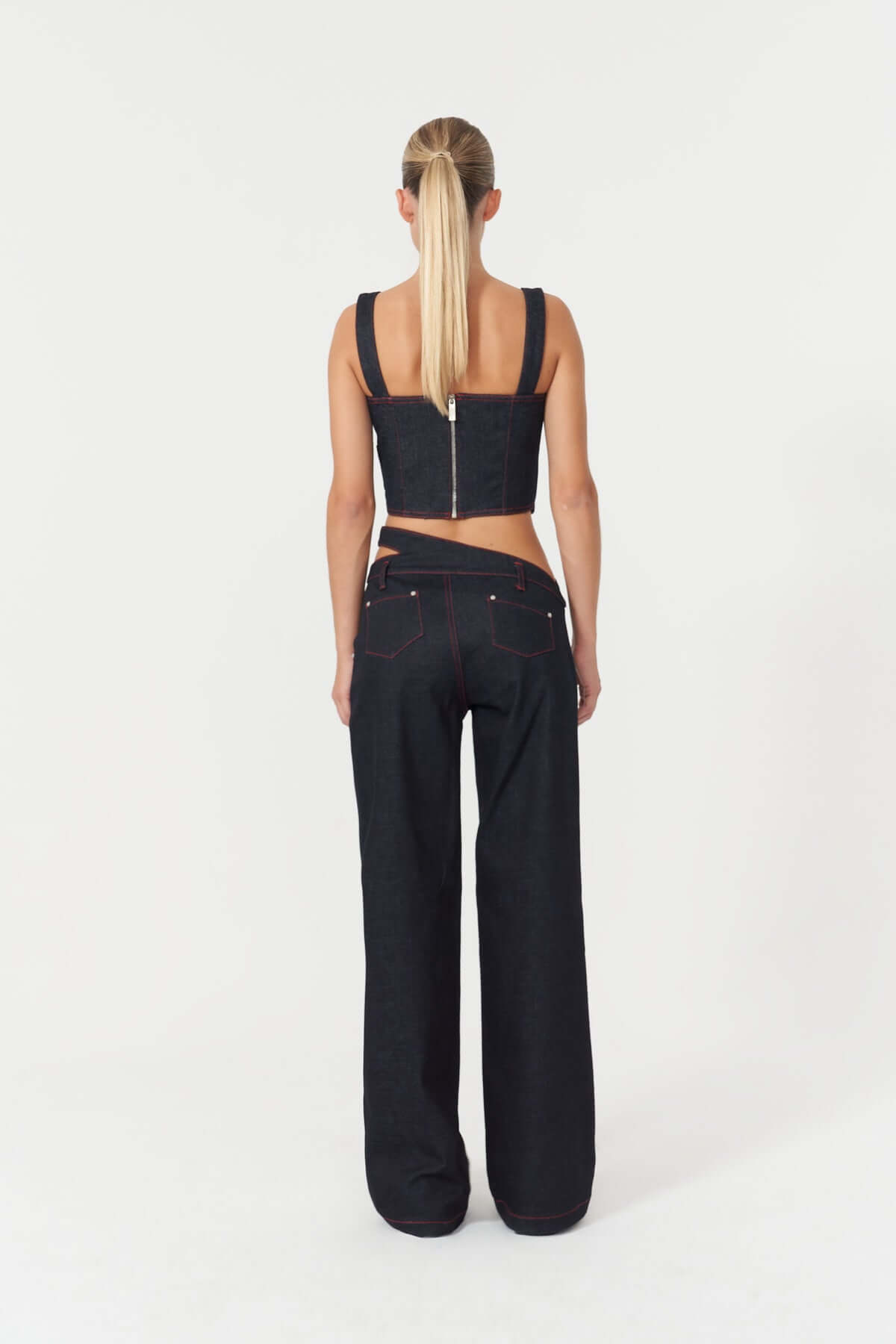 A stylish blue denim corset-style crop top by JENDUE Harvey, with a structured fit, sharp angles, and visible red topstitching.