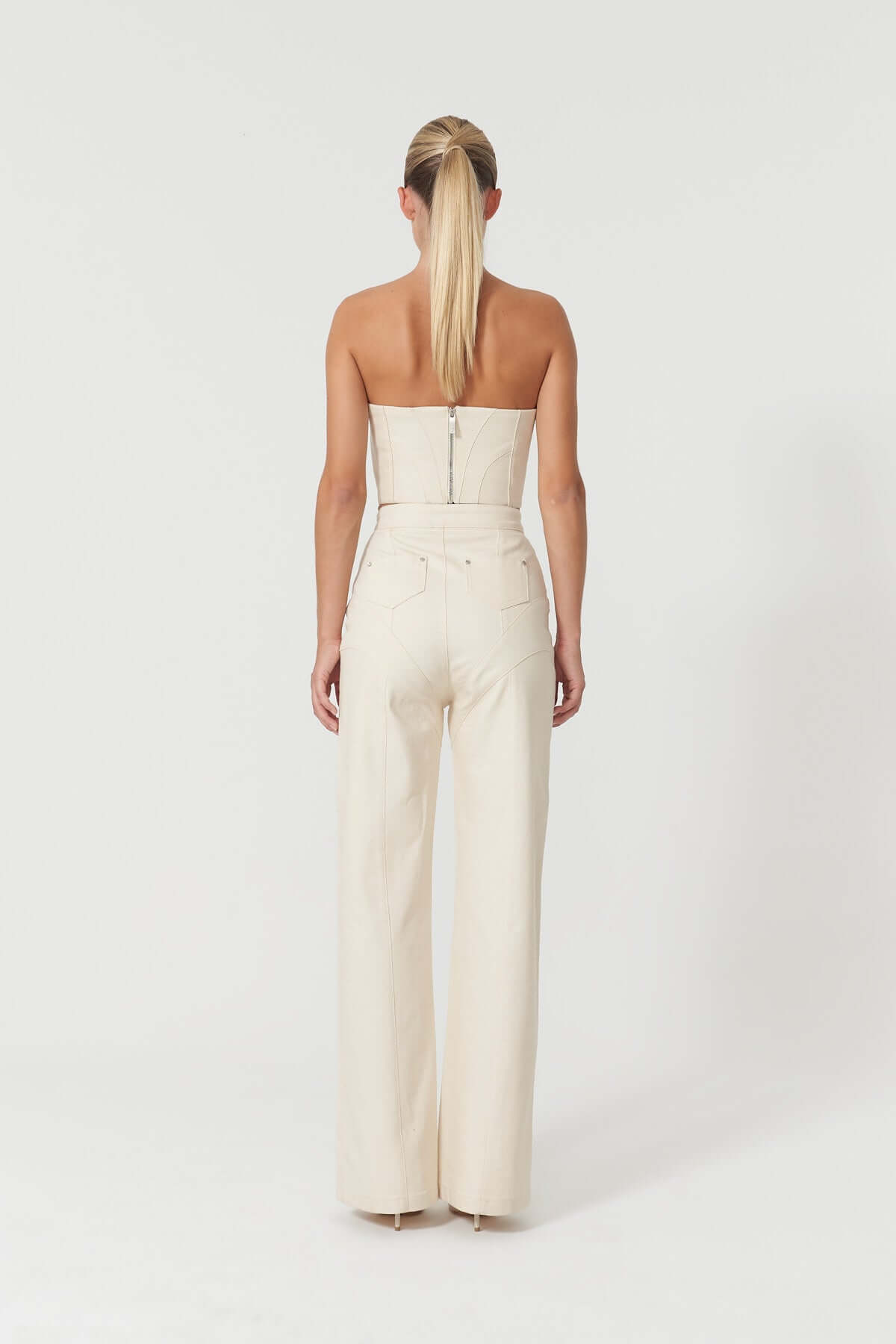 Stylish beige denim crop top by JENDUE Chaby, showcasing a flattering bustier design with intricate paneling and silver hardware.
