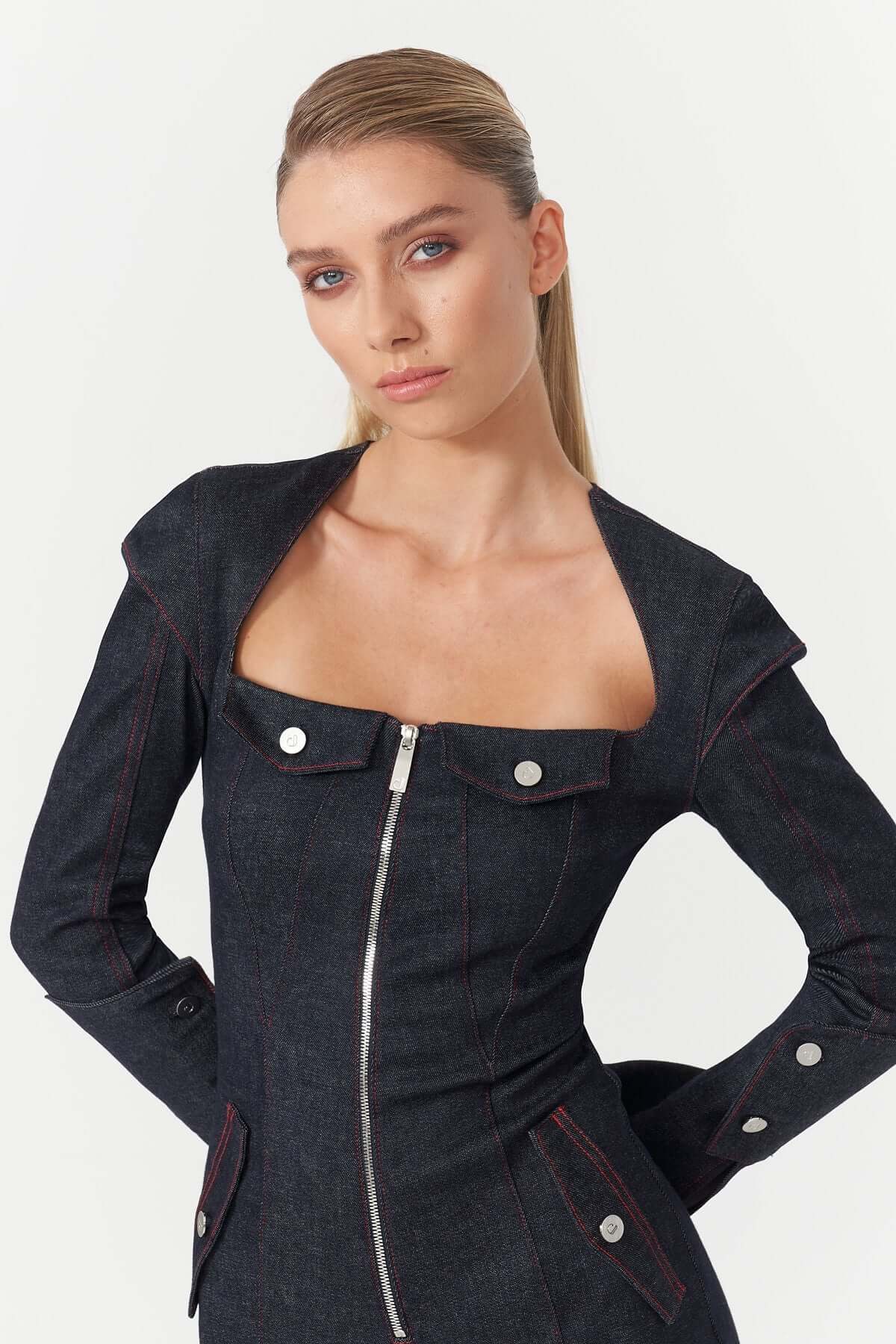 Stylish dark blue denim jumpsuit by JENDUE Harvey, with a flattering silhouette, long sleeves with button details, and a front zipper.