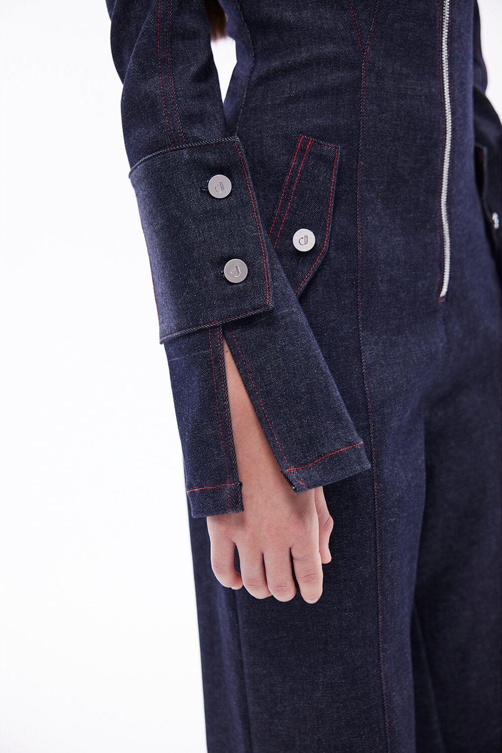 Full view of the JENDUE Harvey Denim Jumpsuit: a dark wash denim one-piece with red topstitching and a modern, tailored fit.