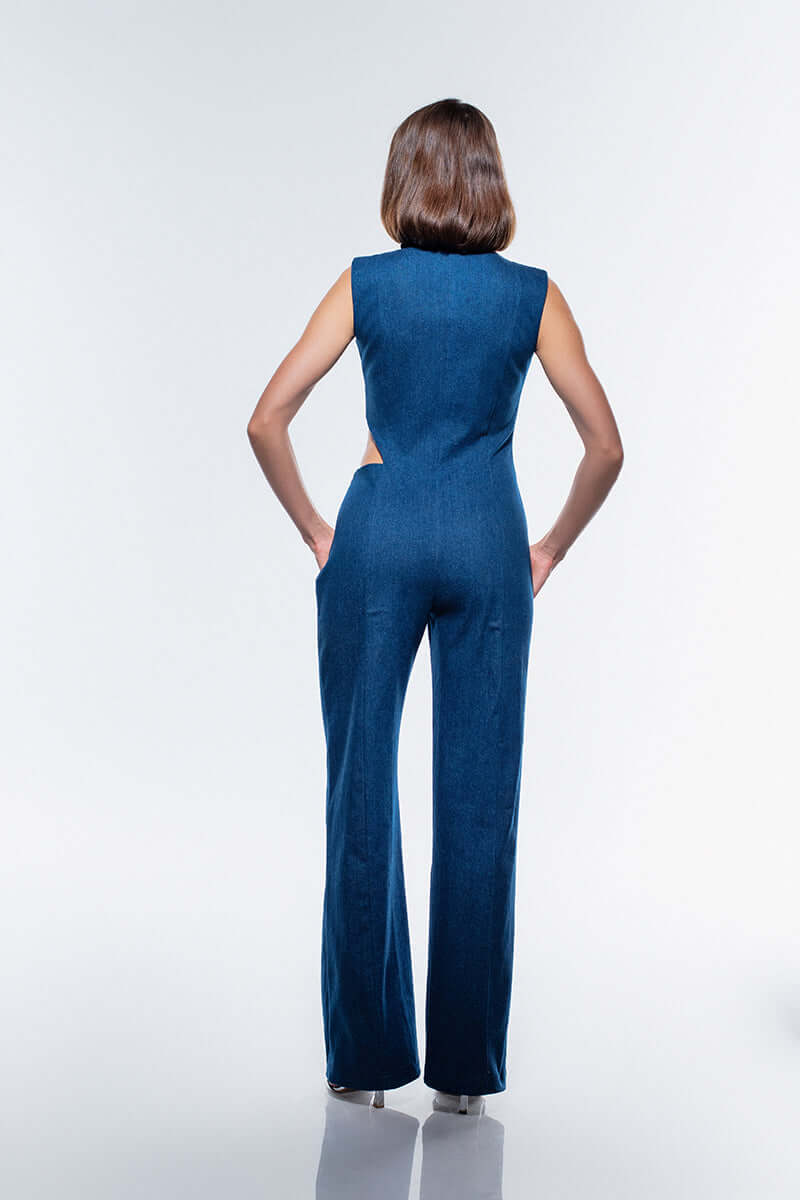 The JENDUE Lustrous Denim Jumpsuit in navy blue, showcasing a striking side cut-out with decorative stitching and a button closure at the top.