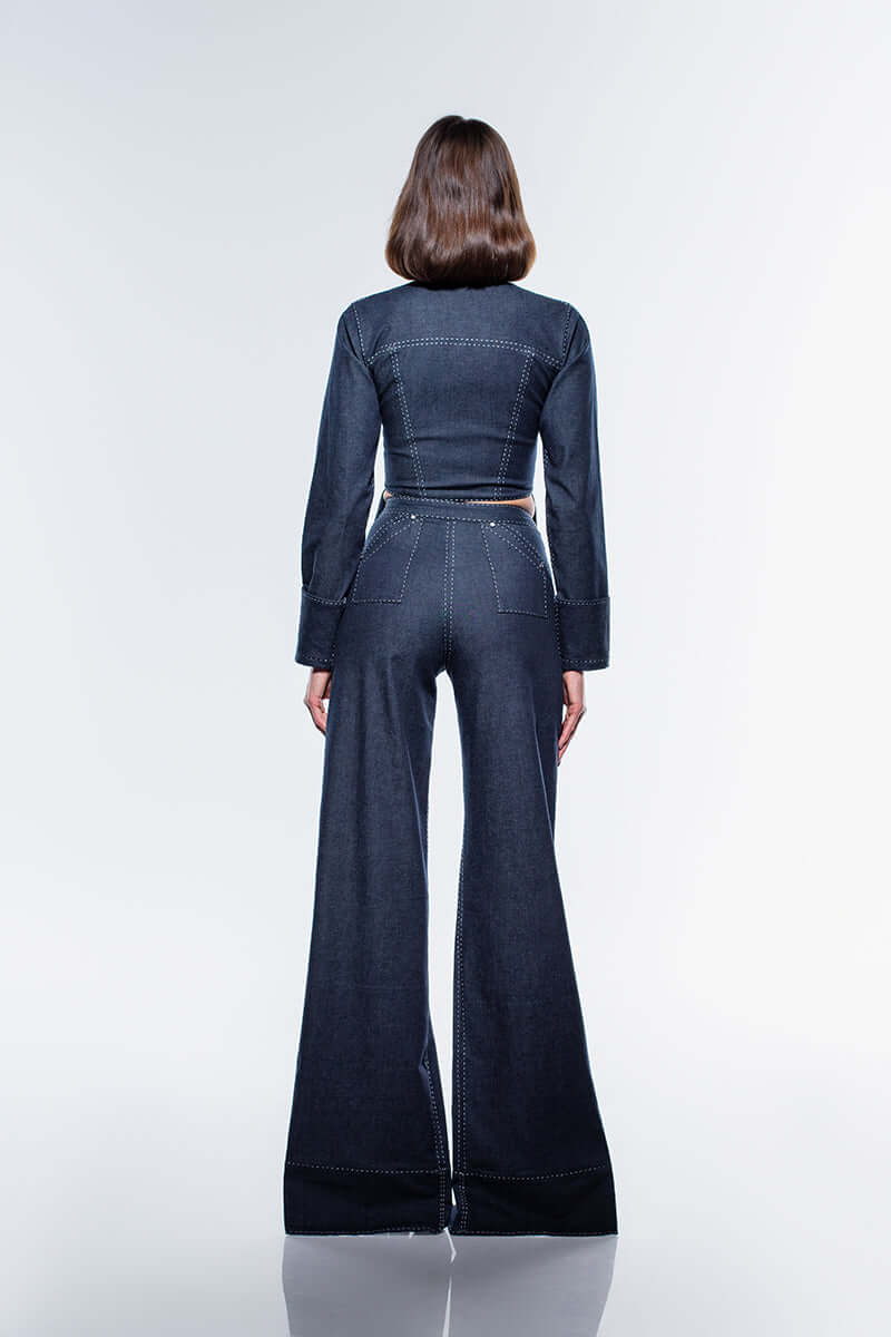 A pair of navy blue, wide-leg denim jeans featuring unique front slits on each leg and white contrast stitching detail.