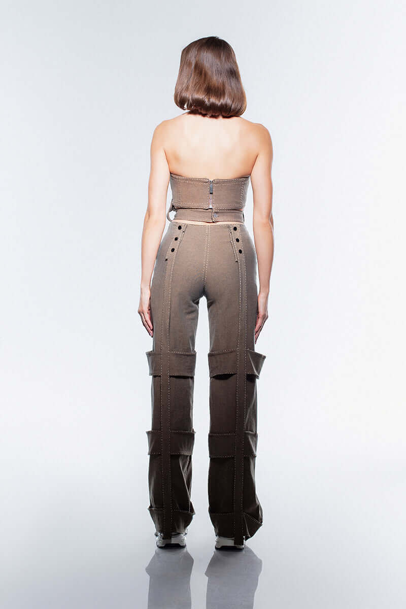 High-waisted, straight-leg brown denim jeans by JENDUE with intricate strap details down both legs and silver eyelets on the waist.